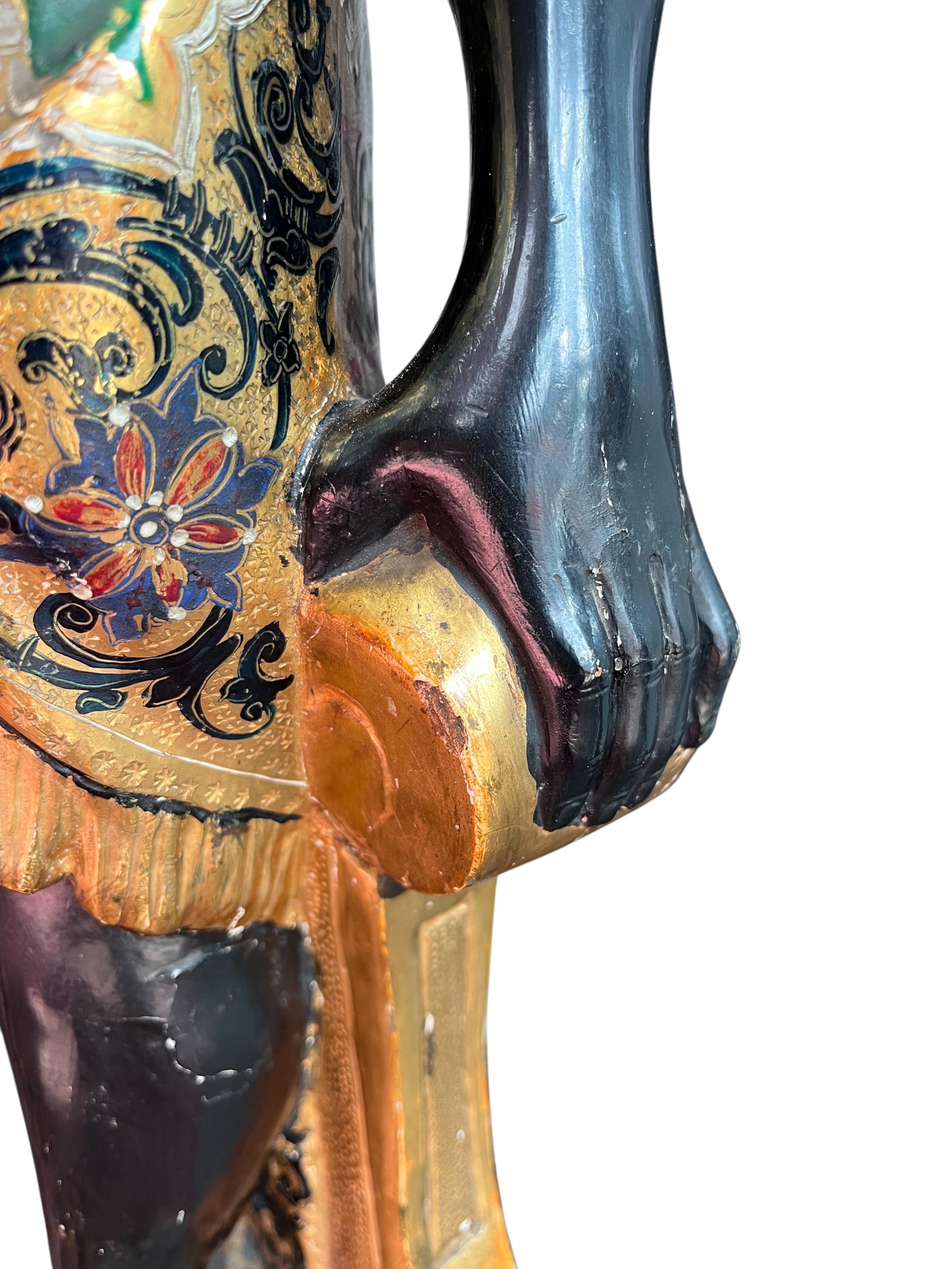 A 19th century Italian carved wood and composition polychrome painted blackamoor torchere, modelled standing with one arm holding a scroll pillar on waisted circular base and lions paw feet, 106cm high